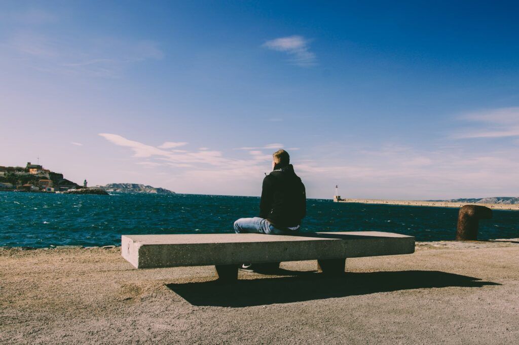 A picture of a man sitting on a bench in deep thought.